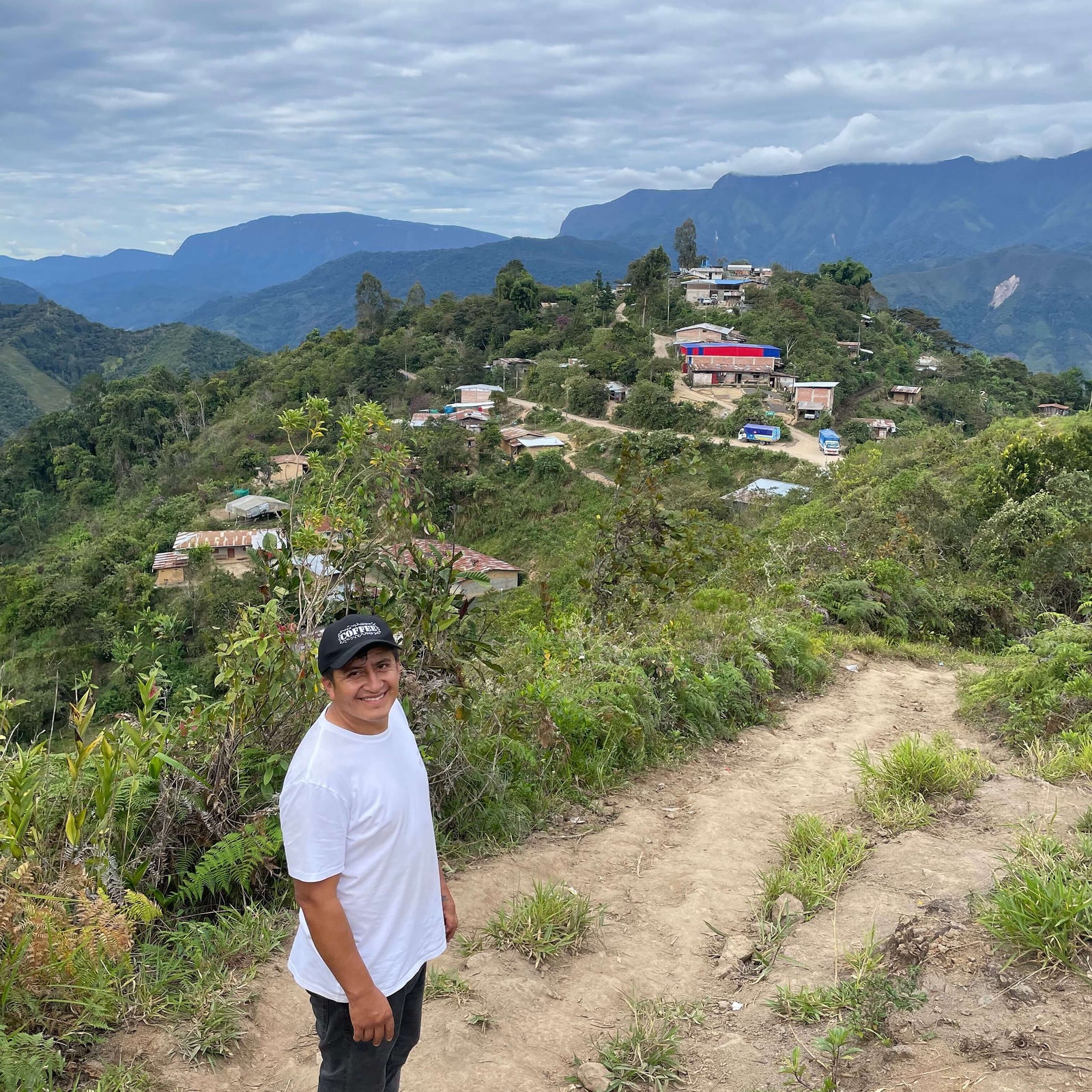 Ebert standing on a dirt path with a scenic view of mountains and houses in the background.