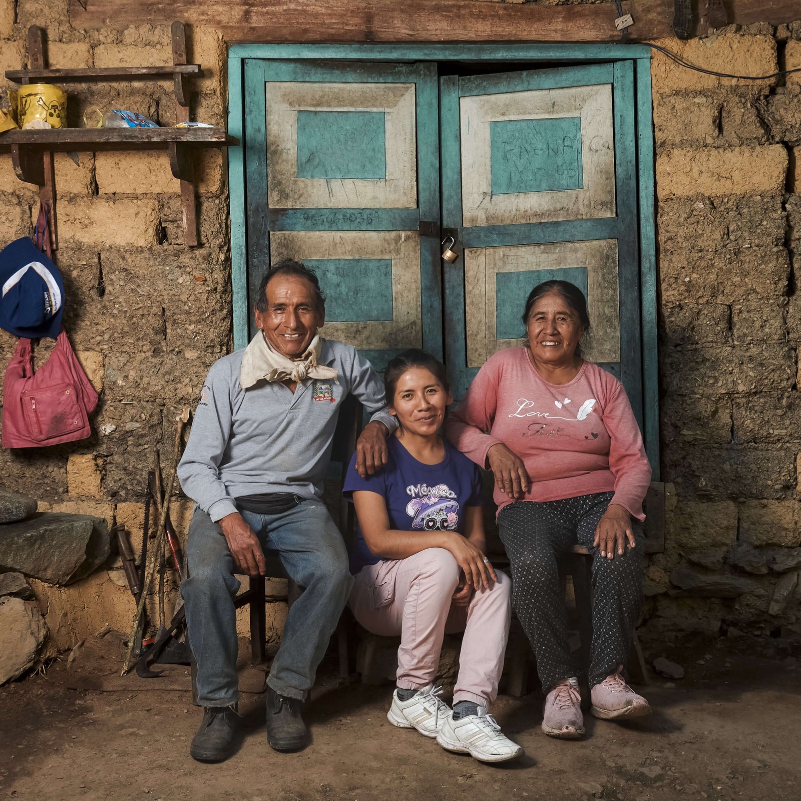 Three people sitting together in front of a rustic wooden door.