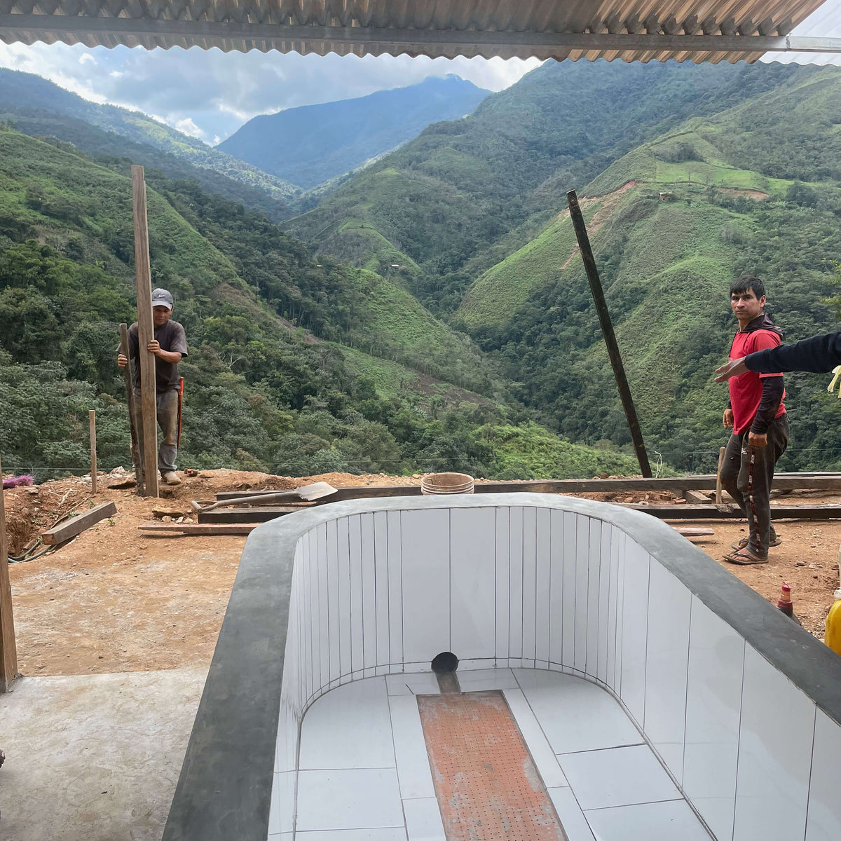Family on site constructing the new beneficio and a scenic mountain view