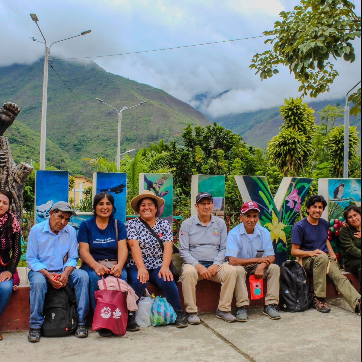 Group of people sitting on a bench with colorful murals and mountains in the background